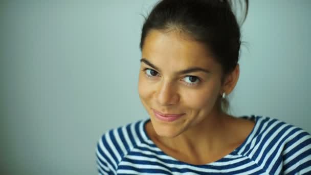 Close up of young smiling lady posing at home and saying hello in a camera. — Stock Video