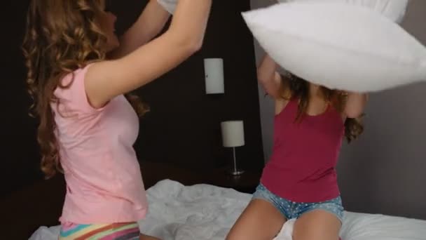 Jóvenes señoras atractivas divirtiéndose y golpeando con almohadas en tiempo de fiesta de pijama . — Vídeos de Stock