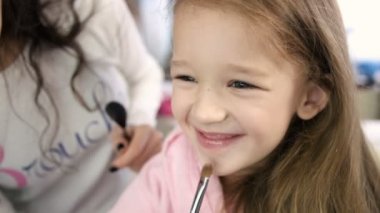 Küçük kız beyaz salonda gülen için fırça ile yapmak yapıyor sanatçı oluşturur. Yakın çekim