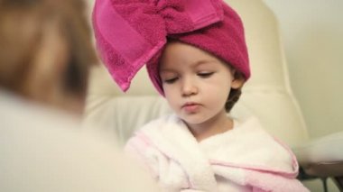 Sevimli küçük kız pembe bornoz ve havlu başında profesyonel salon