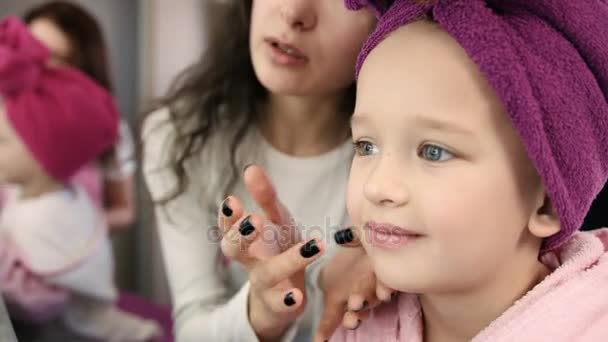 Maquillaje artista haciendo maquillaje con cepillo a la niña sonriente con toalla en la cabeza en el salón blanco. Vista de cerca — Vídeo de stock