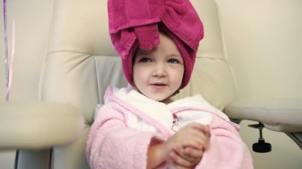 Close up view of pretty little girl in pink robe in professional salon. Beautiful little girl smiling — Stock Video