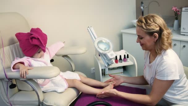 O mestre fazendo massagem para menina bonita na cadeira de pedicure no salão profissional — Vídeo de Stock