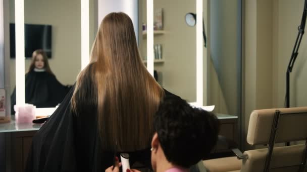 Профессиональный парикмахер, стилист стрижет длинных блондинок с триммером в салоне красоты. Закрыть — стоковое видео