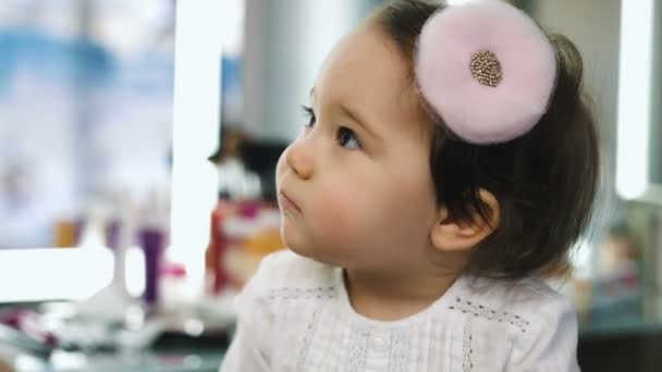 Retrato de una niña bonita sonriendo en el salón de belleza. Vista de cerca . — Vídeo de stock