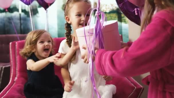 Niña dando caja de regalo con globos a chicas bonitas. vista posterior — Vídeo de stock