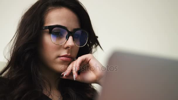 Nahaufnahme Porträt einer jungen attraktiven Frau mit Brille, die auf den Laptop-Bildschirm blickt — Stockvideo