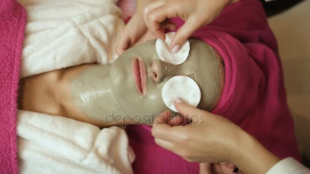 Профессиональный мастер кладет хлопчатобумажные подушечки на лицо женщины глиной в салон красоты. Береги лицо. Лечение. Закрыть — стоковое видео