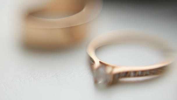 Золотые обручальные кольца с бриллиантами Акцент на обручальные кольца на белом фоне. Крупный план — стоковое видео
