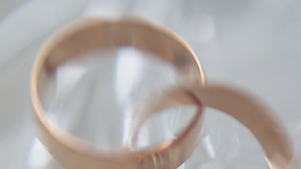 Золотые обручальные кольца с бриллиантами Акцент на обручальные кольца на белом фоне. Крупный план. Потерял фокус — стоковое видео