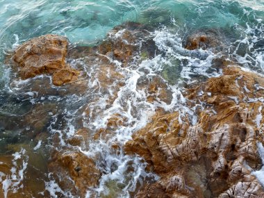 Kayalık sahilde berrak su dalgası köpüğü