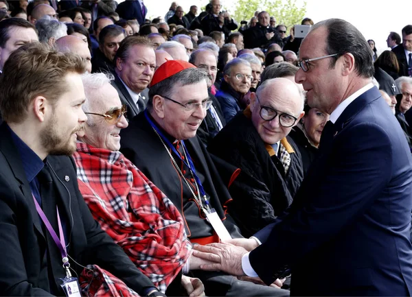 O presidente francês François Hollande, à direita, saúda o cantor Charles Aznavour, segundo da esquerda, durante um serviço fúnebre no complexo memorial do genocídio armênio Tsitsernakaberd em Erevan, Armênia, sexta-feira, 24 de abril de 2015 . Fotos De Bancos De Imagens