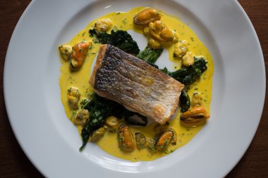 Ispanak yaprakları ve Mussel sos pişmiş filleted balık