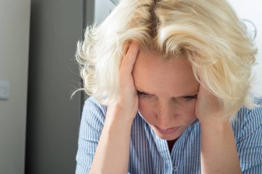 Çizgili gömlekli kadında umutsuzluk elleriyle kafa tutar