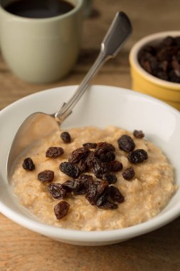 Kase yulaf ezmesi ve ahşap zemin üzerine kuru üzüm