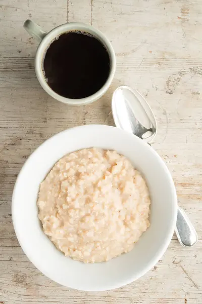 ชามข้าวโอ๊ตและกาแฟบนพื้นหลังไม้ — ภาพถ่ายสต็อก