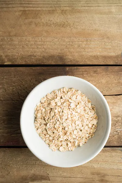 Cuenco de avena cruda sobre fondo de madera con espacio de copia — Foto de Stock