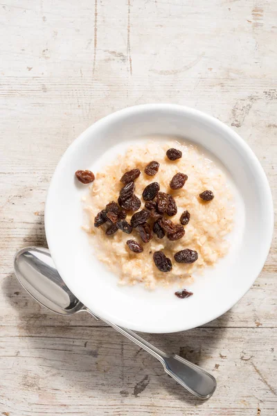 Bowl of Porridge Oats and raisins on White Wooden Background — Stock Photo, Image