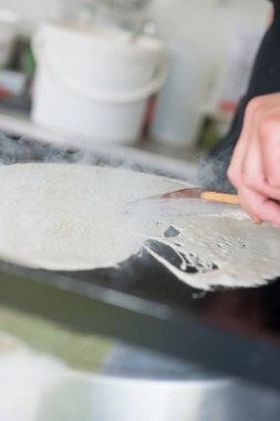 Ahşap bir krep kazıyıcı ile sıcak ızgara üzerinde krep yayma