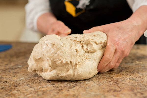 Fresh bread dough being mixed by hand on a stone countertop