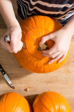 Bir balkabağı taç oymak için bir bıçak kullanarak ellerin havai çekim