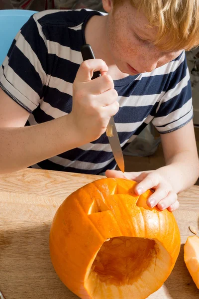 Balkabağı feneri oyan genç bir çocuk.