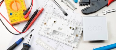 Multimetre, tornavidalar, tel kesiciler, matkap uçları, anahtarlar ve soketler dahil olmak üzere çeşitli elektrikli araç ve bileşenlerin Web banner formatı çekim.