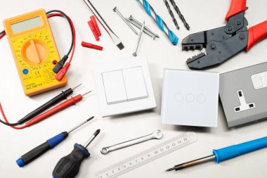Multimetre, tornavidalar, tel kesiciler, matkap uçları, anahtarlar ve soketler dahil olmak üzere çeşitli elektrikli aletler ve bileşenler.