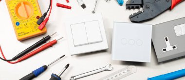 Multimetre, tornavidalar, tel kesiciler, matkap uçları, anahtarlar ve soketler dahil olmak üzere çeşitli elektrikli aletler ve bileşenler. Web banner biçimi.