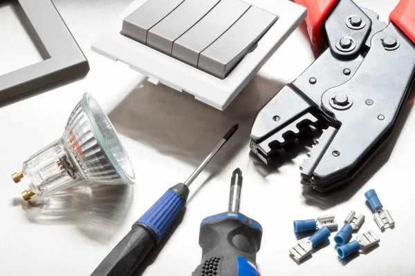 Selection of electrical contractors tools including wire cutters, screwdrivers, clips and a light switch.