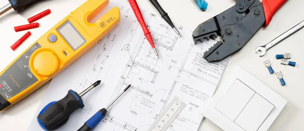 Bir multimetre, tornavida, tel kesiciler ve bir ışık anahtarı da dahil olmak üzere ev planları elektrikli müteahhitler araçları bir ürün yelpazesine web sitesi afiş formatı atış.
