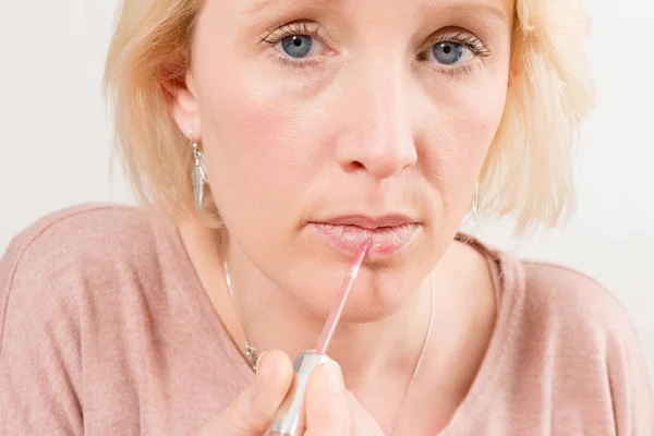 Primer plano de la mujer aplicando brillo en los labios Mirada directa — Foto de Stock