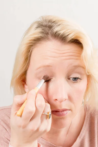 Senhora loira aplicando sombra de olhos — Fotografia de Stock