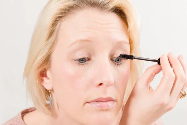 Close-up de senhora loira aplicando maquiagem rímel — Fotografia de Stock