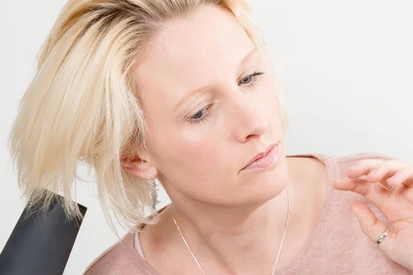 Rubia señora secándose el pelo con secador de pelo eléctrico — Foto de Stock