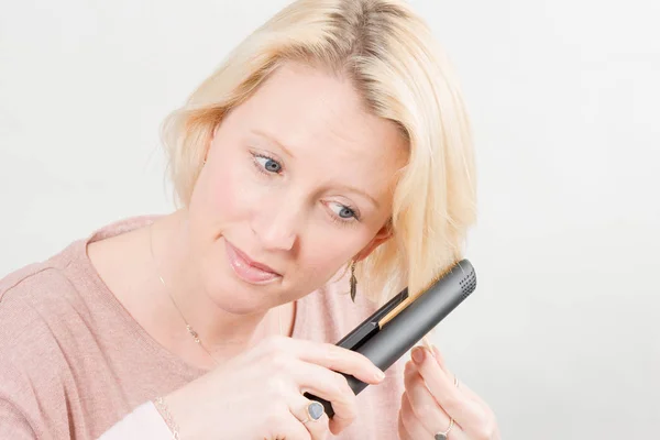 Mujer peinando su cabello con un hierro alisado Copiar espacio — Foto de Stock