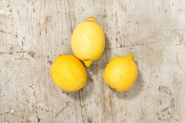 Три лимона на деревянной поверхности — стоковое фото