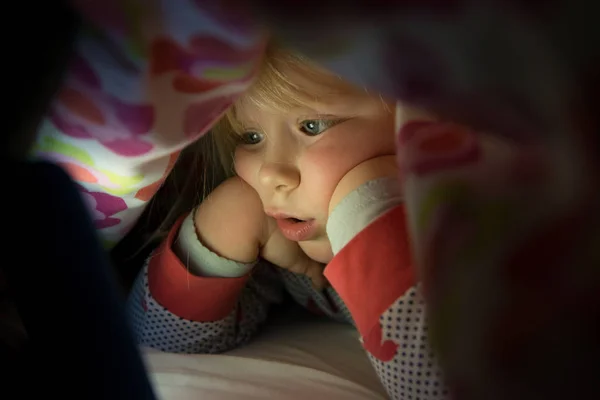 Ragazza in pigiama avvolto in coperta guardando a schermo Tablet — Foto Stock