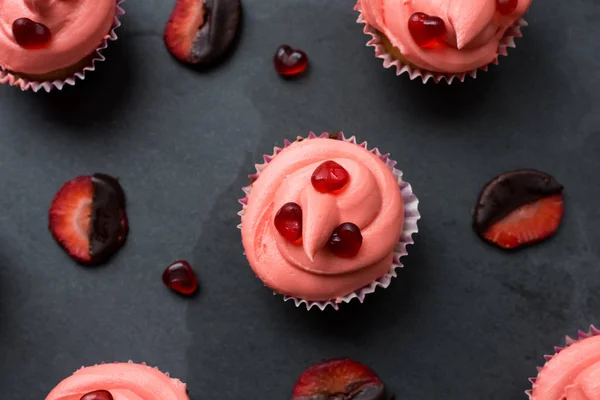 Cupcakes rosados con corazones de caramelo y fresa bañada en chocolate — Foto de Stock