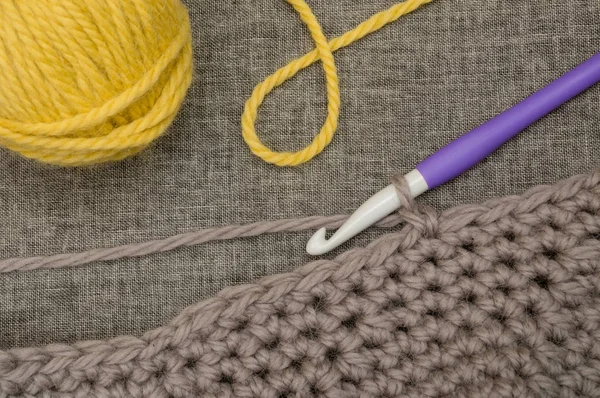 Gancho de tricô, lã cinza de malha e bola de fio amarelo — Fotografia de Stock