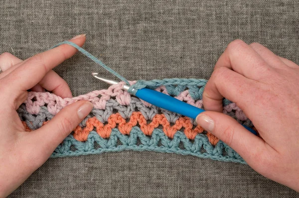 Hands Knitting Hook and Crocheted Band with Wavy Color Pattern