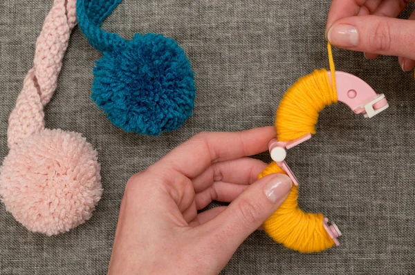 Hände schleifen gelbes Garn um den Pom-Pom-Hersteller — Stockfoto