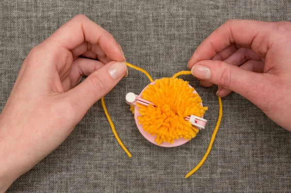 Mains empaquetant le fil jaune dans un fabricant de pompon — Photo