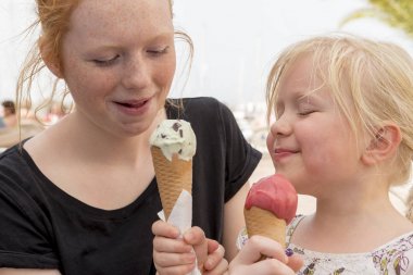 Genç kadın ve küçük kızı dondurma koni üzerinde paylaşımı
