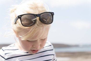 Aşağıda arayanlar güneş gözlüğü ile beyaz çizgili gömlek, küçük kız