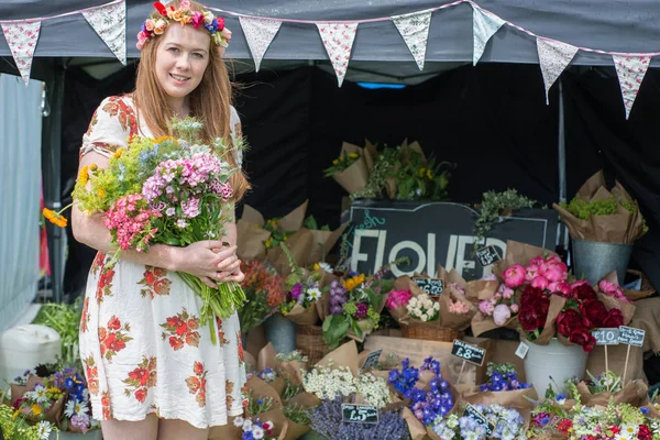 Chica sosteniendo racimo de flores por su tienda de flores al aire libre — Foto de Stock
