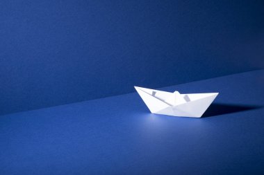 Mavi zemin ve duvar arka plan üzerinde beyaz kağıt tekne