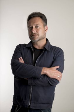 Gri arka plan üzerinde çapraz kolları olan sakallı adam portresi