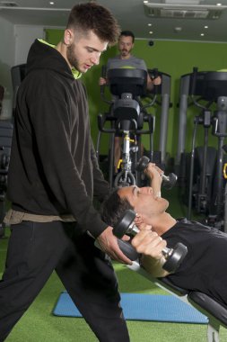 Göğüs Flyes spor salonunda yaparken istemci yardımcı spor eğitmeni