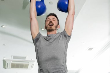 Atletik adam iki ağır Kettlebells kaldırma